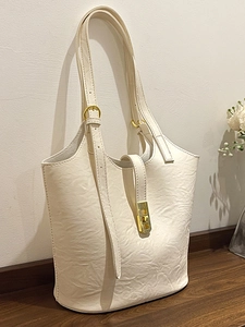 Minimalist cream leather tote bag with gold hardware on a wooden table for daily commute