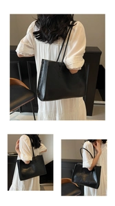 Close-up detail of the black leather texture and sleek handles on a large tote bag