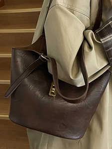 Retro deep brown large capacity tote bag with gold hardware worn on a model shoulder