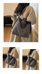 Detail view of large grey canvas tote bag with brown leather strap and side metal buckle