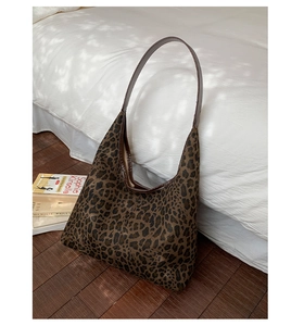 Detailed close-up of leopard print shoulder bag with glossy texture on white bedding