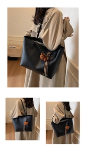 Detail der schwarzen Shopper Tasche mit Bärenanhänger und Quasten am beigen Trenchcoat