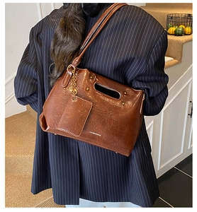 Detailed view of deep brown vintage leather bag with a small matching wallet pendant