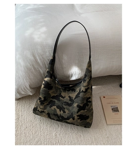 Detail view of large leopard print tote bag with black leather straps on white rug