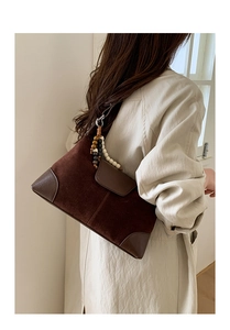 Detail of suede crossbody bag with decorative wooden beads and smooth leather patchwork