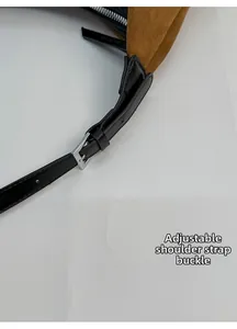 Detail of adjustable leather shoulder strap with silver buckle on brown suede bag