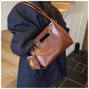 Detail of vintage brown oil wax leather handbag with rivet accents and small coin pouch