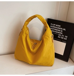 Détail du sac cabas en nylon jaune montrant la texture plissée et la fermeture éclair double