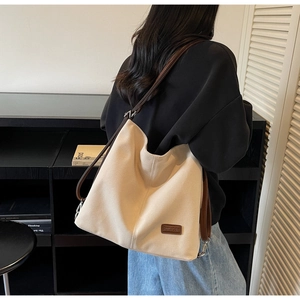 Detail of canvas tote bag with brown leather strap and brand logo in a lifestyle setting