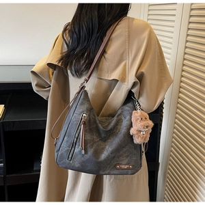 Detail of dark grey retro leather tote bag with brown plush puppy charm and adjustable strap