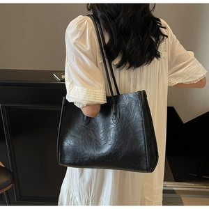 Detail of minimalist black leather tote bag showing spacious design and sturdy shoulder straps
