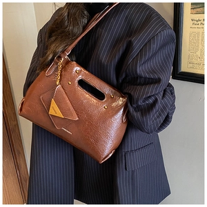 Detail of vintage brown glossy leather handbag with integrated handle and fashion coin purse