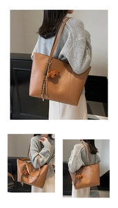 Detail einer großen braunen Shopper-Tasche mit Bären-Anhänger und Quasten-Detail