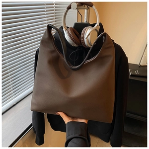 Detail of dark brown vintage hobo tote bag held against a home lifestyle background