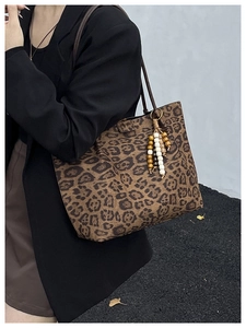 Dettaglio della borsa tote leopardata con ciondolo di perline e tracolla in pelle marrone scuro