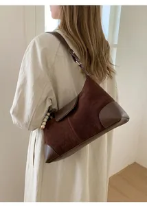 Détail d'un sac à bandoulière vintage marron foncé avec élégant charme en perles blanches