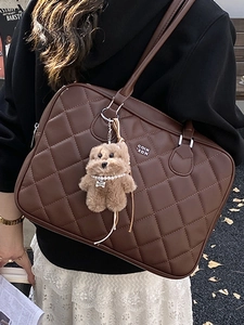 Brown quilted leather tote bag with a dog charm shown in a street fashion style