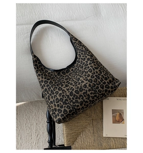 Top view of large leopard print tote bag with black leather shoulder strap and soft texture