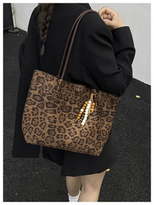 Dettaglio della borsa tote leopardata con ciondolo in perline di legno e tracolle