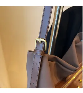 Detail of adjustable dark brown leather shoulder strap with vintage gold buckle