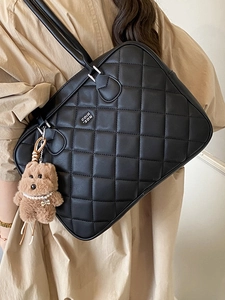 Quilted black leather tote bag with elegant brown teddy bear charm and twin straps
