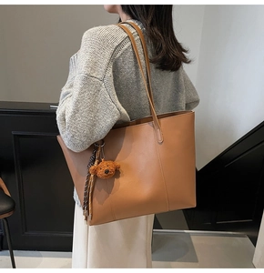 Braune Shopper-Tasche aus Kunstleder mit Bärenanhänger und Quasten an der Schulter