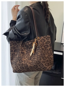 Dettaglio della borsa tote leopardata con tracolla marrone e ciondolo in perline di legno