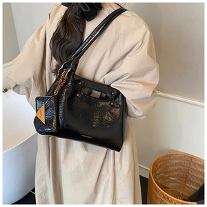 Chic black patent leather shoulder bag with gold chain and coin purse detail on a model