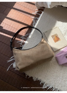 Detailed texture of camel suede shoulder bag with vertical seam on white rug