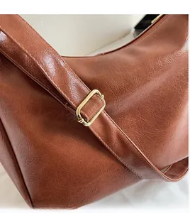 Détail de la bandoulière en cuir marron réglable avec boucle en métal doré poli