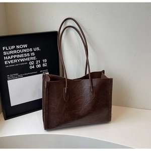 Detail of vintage dark brown tote bag showing the oily leather texture and shoulder straps