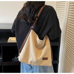 Detailed shot of beige canvas tote bag with adjustable brown straps and leather logo patch