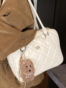 White quilted tote bag with puppy charm shown on model in stylish brown suede coat