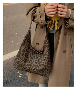 Detail of leopard print hobo bag in canvas with brown strap shown in outdoor setting