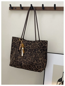 Dettaglio della borsa tote leopardata con ciondolo a nappine e tracolle marroni