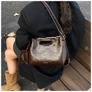 Detail of a vintage dark brown oil wax leather shoulder bag in an autumn outdoor street setting