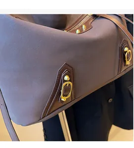 Close-up of brown suede tote bag featuring vintage metal rivets and buckle details