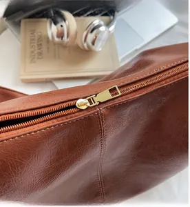 Gros plan sur la fermeture éclair dorée lisse du grand sac fourre-tout en cuir marron