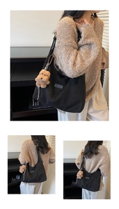 Detail view of large black tote bag with brown plush pendant and leather brand tag