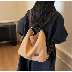 Rear view of a model wearing a large canvas tote bag with brown leather straps