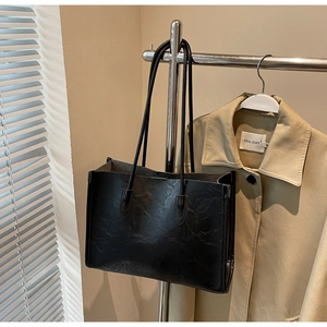 Detail of black tote bag with wrinkled leather texture hanging on a metal rack