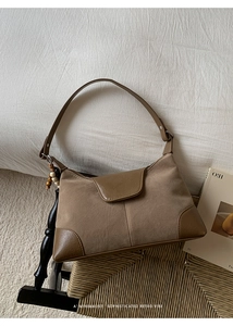 Detail view of a retro brown crossbody bag with matte texture and decorative beaded charm