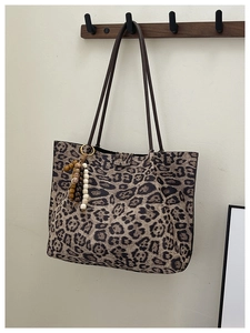Dettaglio della borsa tote leopardata grande con ciondolo in legno e spalline lunghe