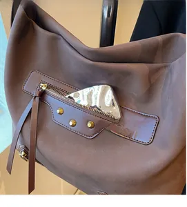 Detail of vintage brown tote featuring functional zipper pocket with long fringe tassels