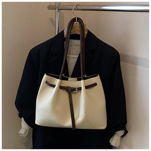 Detail view of the elegant canvas tote bag with brown leather straps on a hanger