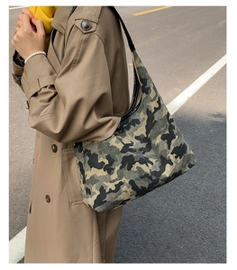 Close-up of camouflage canvas shoulder bag with wide strap on model in trench coat