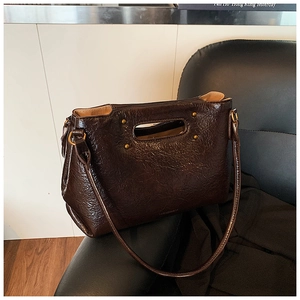 Detail view of dark brown vintage leather handbag with pleated texture on a leather seat