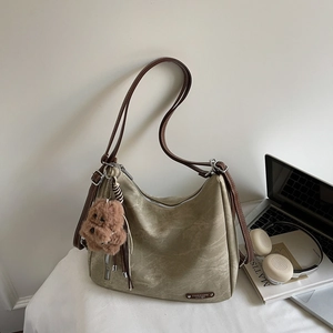 Detail of vintage canvas tote bag with brown leather straps and teddy bear pendant
