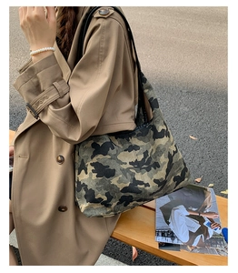 Close-up of a large camouflage tote bag styled with a khaki trench coat for city commute