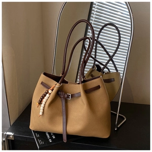 Detailed macro view of Earth-tone canvas tote bag with brown leather handles and bead charm